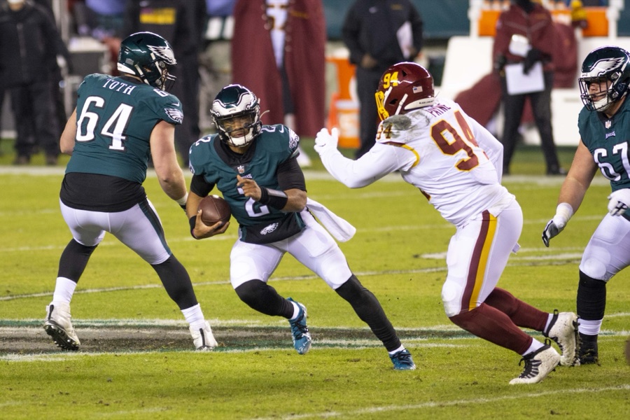 Brett Toth in January 2021, nameplate TOTH over number 64 in a Philadelphia Eagles midnight green home jersey, pulling out of his stance to lead-block for quarterback Jalen Hurts while Washington's Daron Payne, number 94, comes around the edge. This site holds no photograph of Toth in a 49ers uniform.