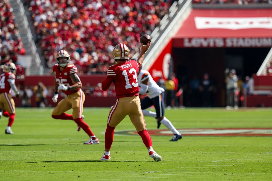 Brock Purdy, seen from behind in the 49ers' home red jersey and gold trousers, throws a pass against Denver at Levi's Stadium on Oct. 4.