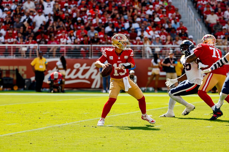 Brock Purdy, in the 49ers' home red jersey and gold trousers, sets in the pocket with the ball in both hands against Denver at Levi's Stadium on Oct. 4.