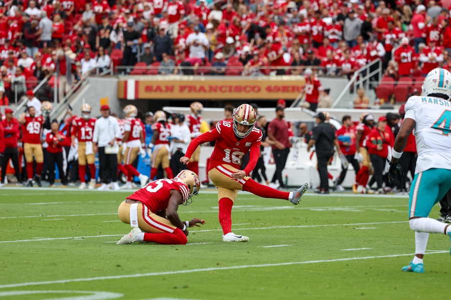 Eddy Pineiro kicks off the hold of Corliss Waitman in a red 49ers home uniform against Miami at Levi's Stadium.