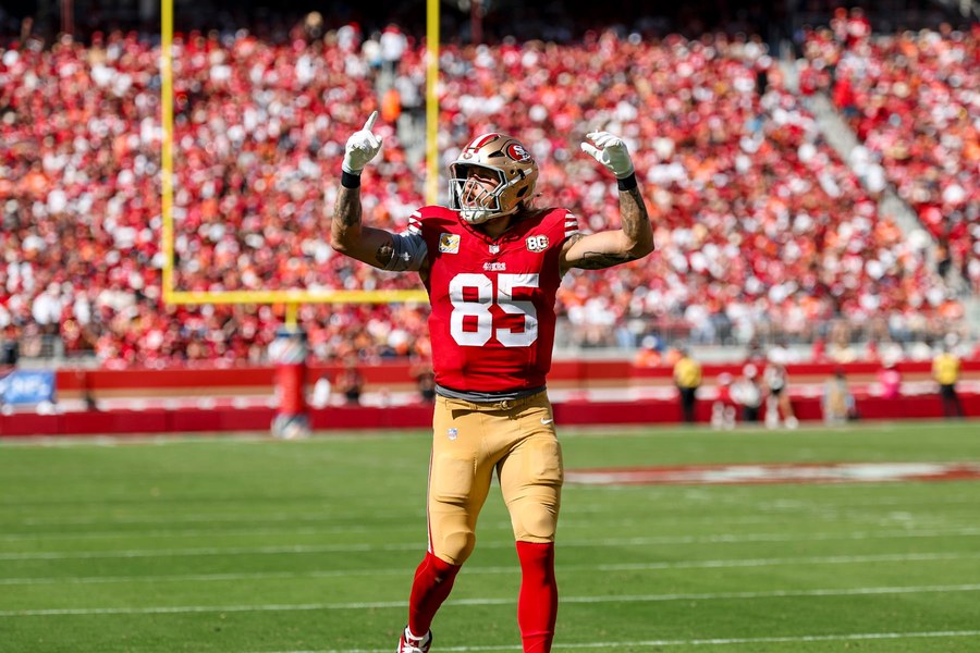 George Kittle, number 85, in the 49ers' red home jersey and gold trousers, both arms raised to a crowd dressed in red at Levi's Stadium, from the Denver game on October 4.
