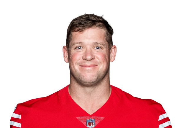 Jon Weeks in a studio roster headshot against a white background, wearing the 49ers scarlet home jersey with the NFL shield at the collar and the white and gold sleeve stripe. A posed portrait, not a photograph from any practice or game described here.
