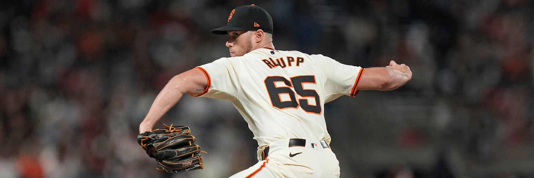 Landen Roupp mid-delivery in the Giants' cream home uniform, his name and number 65 legible across the back of the jersey.