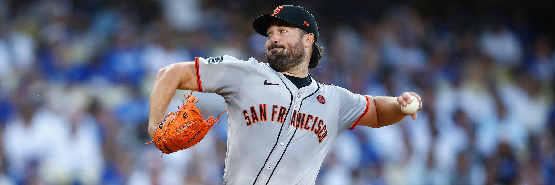 Robbie Ray, when he pitched for the Giants, in the road gray uniform and black SF cap, mid-delivery with his orange glove held out in front of him.