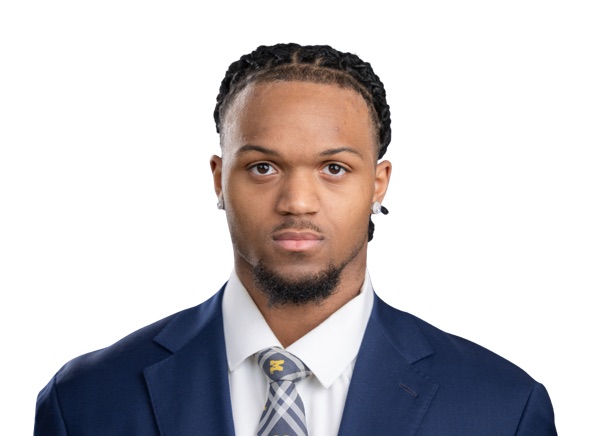 Troy Bowles, Michigan linebacker, in a posed roster portrait against a white background, wearing a navy suit jacket, a white shirt and a gray checked tie carrying a small maize block M. No jersey and no number are in the frame.