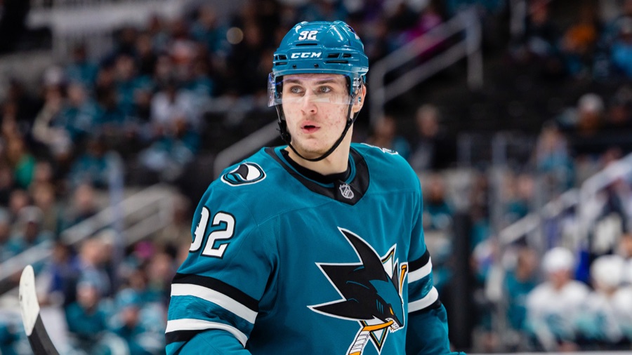 Igor Chernyshov in the Sharks' teal home sweater, helmet on and chin strap fastened, looking off to his right during a stoppage at SAP Center.