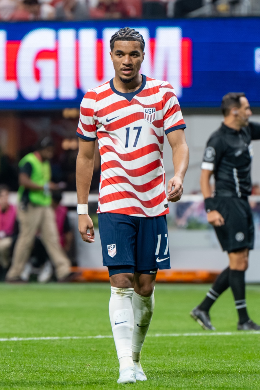 Malik Tillman walks across the pitch in the United States home shirt of red and white wavy stripes during the friendly against Belgium at Mercedes-Benz Stadium on March 28, 2026, six months before the Mexico match, with the stadium board behind him showing Belgium's name.
