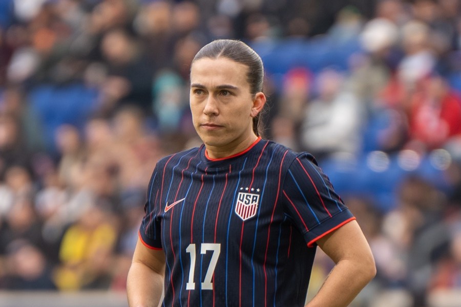 Sam Coffey in the United States navy pinstripe shirt, hair pulled back, looking off to one side with a crowd blurred behind her, at the SheBelieves Cup match against Colombia on March 7, 2026.