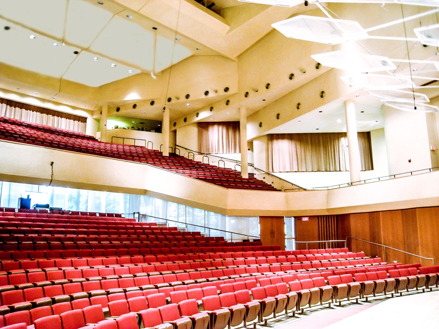 The interior of Thorne Auditorium at Northwestern's law school in Chicago, photographed in 2011, looking across several hundred tiered red seats toward a curved balcony and a curtained stage. Every seat in the frame is empty.