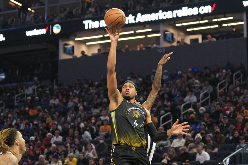Moses Moody, in the Warriors black and gold jersey with the number 4, releasing a jump shot over a defender's outstretched hand at Chase Center.