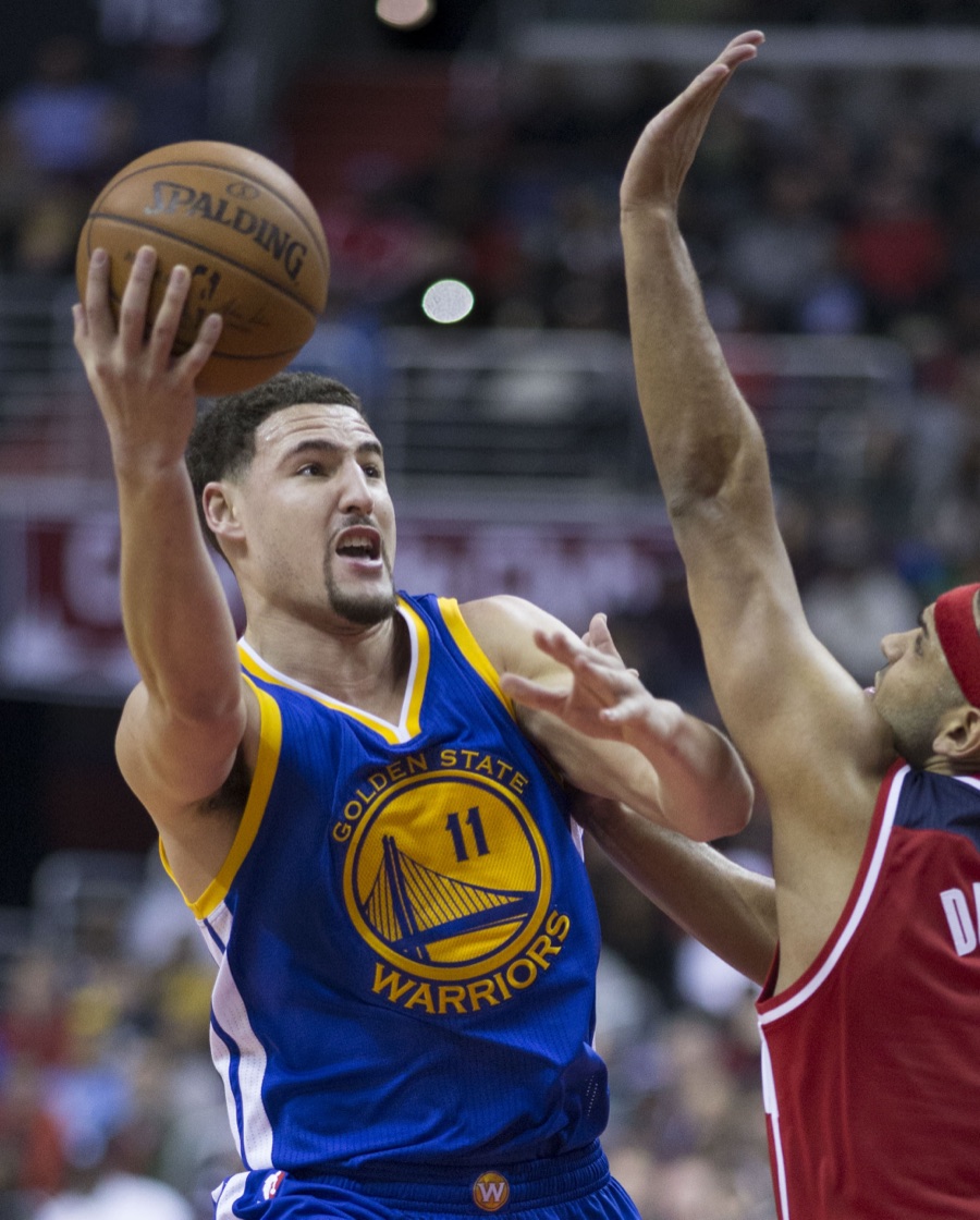 Klay Thompson in the Warriors road blue jersey with the number 11, driving to the basket past a Washington defender in red. The photograph is from February 2016, ten years before this piece, and he has not worn that uniform since 2024.